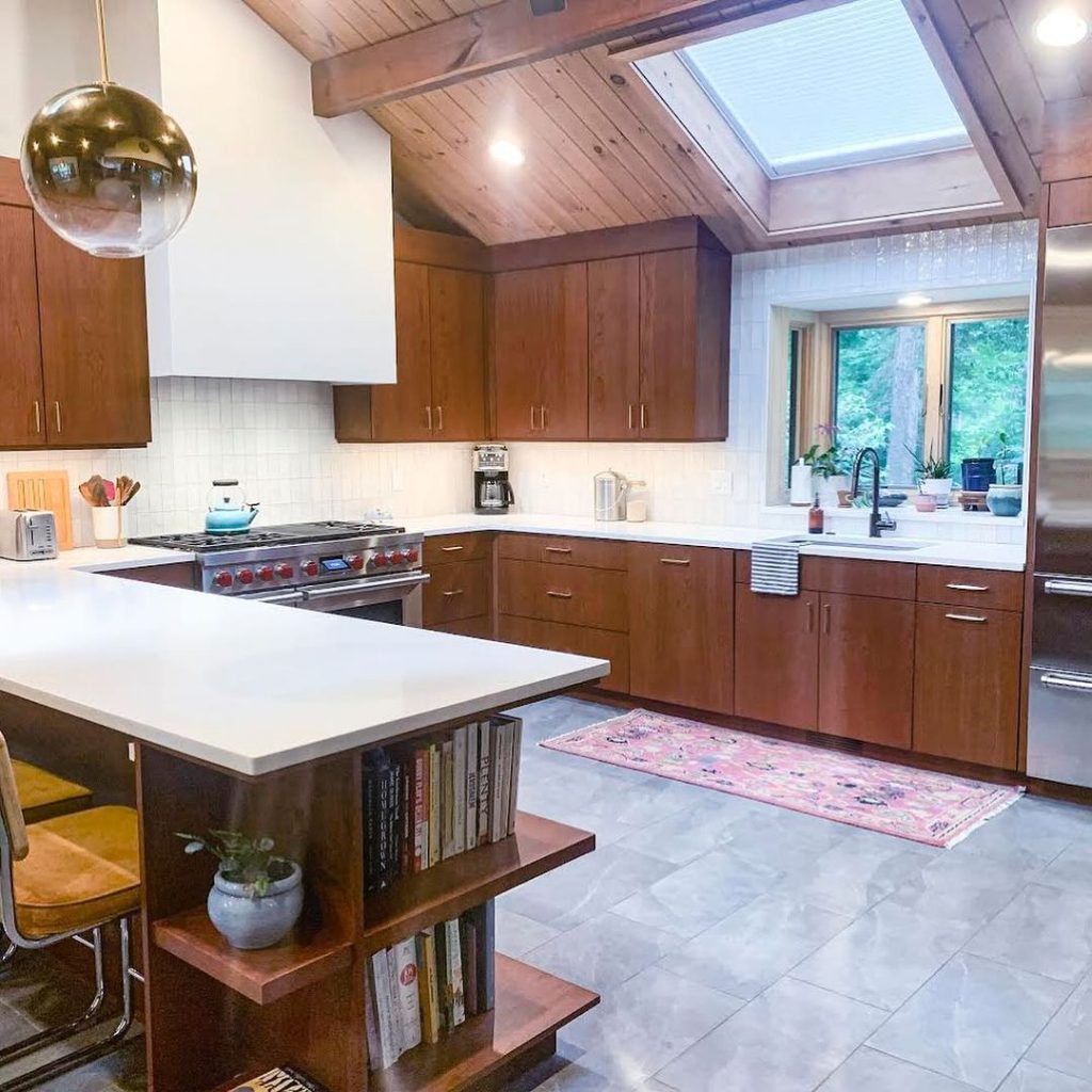 Skylit kitchen with wooden cabinets and book storage island