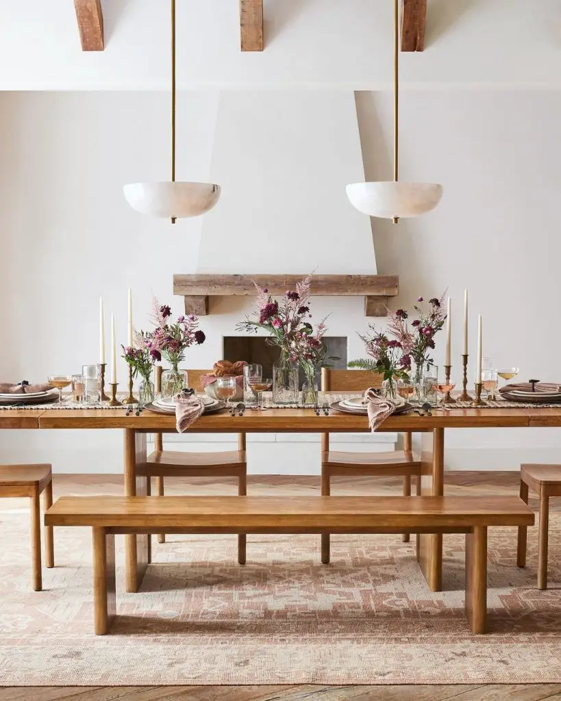 Modern farmhouse dining room with wooden table floral centerpieces and pendant lighting above fireplace