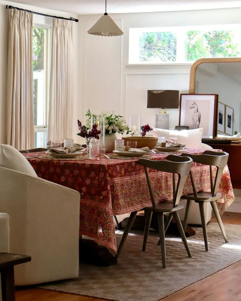 Modern dining room with red patterned tablecloth, gray chairs, and elegant holiday table settings