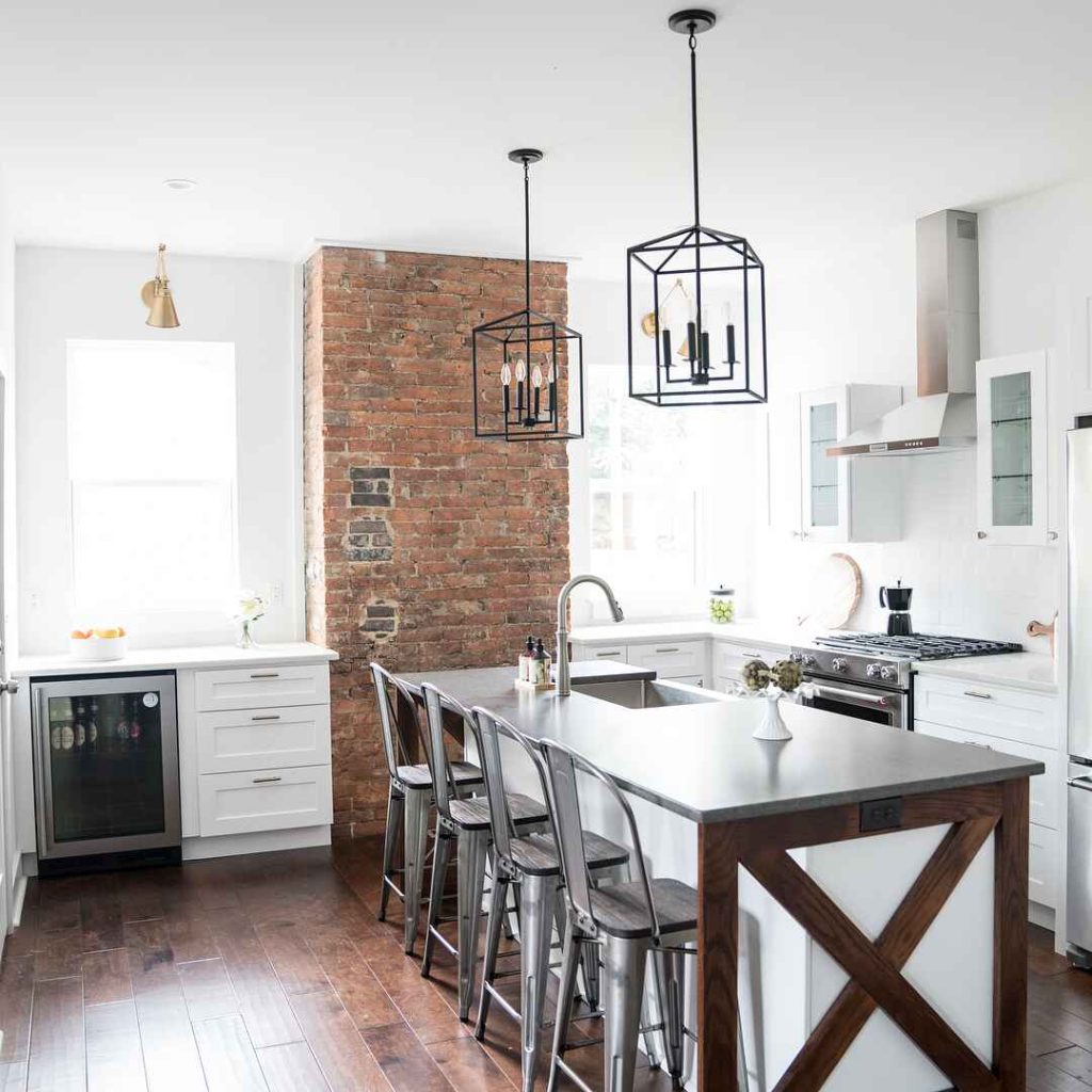 White kitchen with brick wall and geometric pendant lights