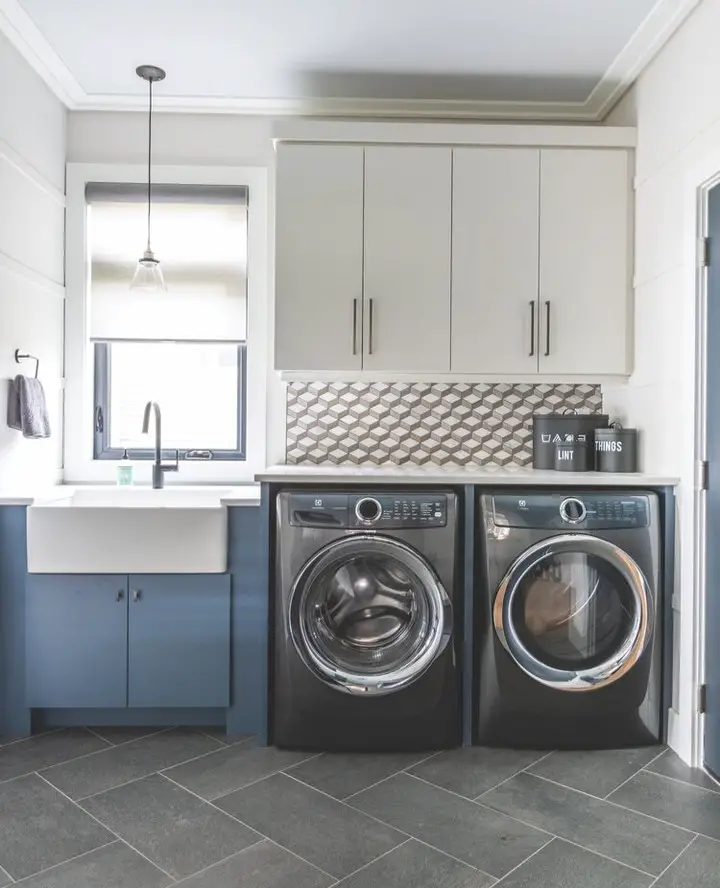 Geometric inspired laundry room with navy cabinets white backsplash and modern appliances