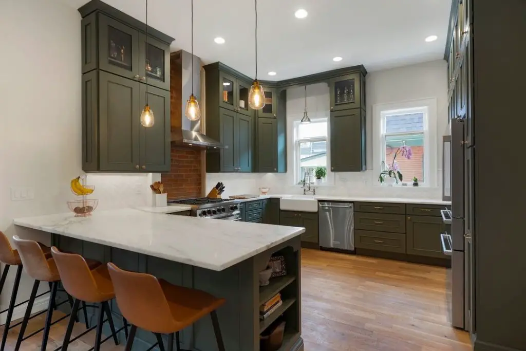 Sage green kitchen with marble counters and pendant lights