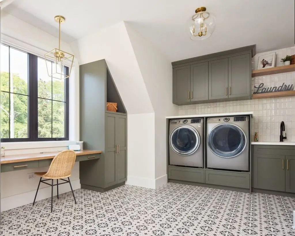 Dual purpose laundry room with built in desk space patterned floors and sage cabinets