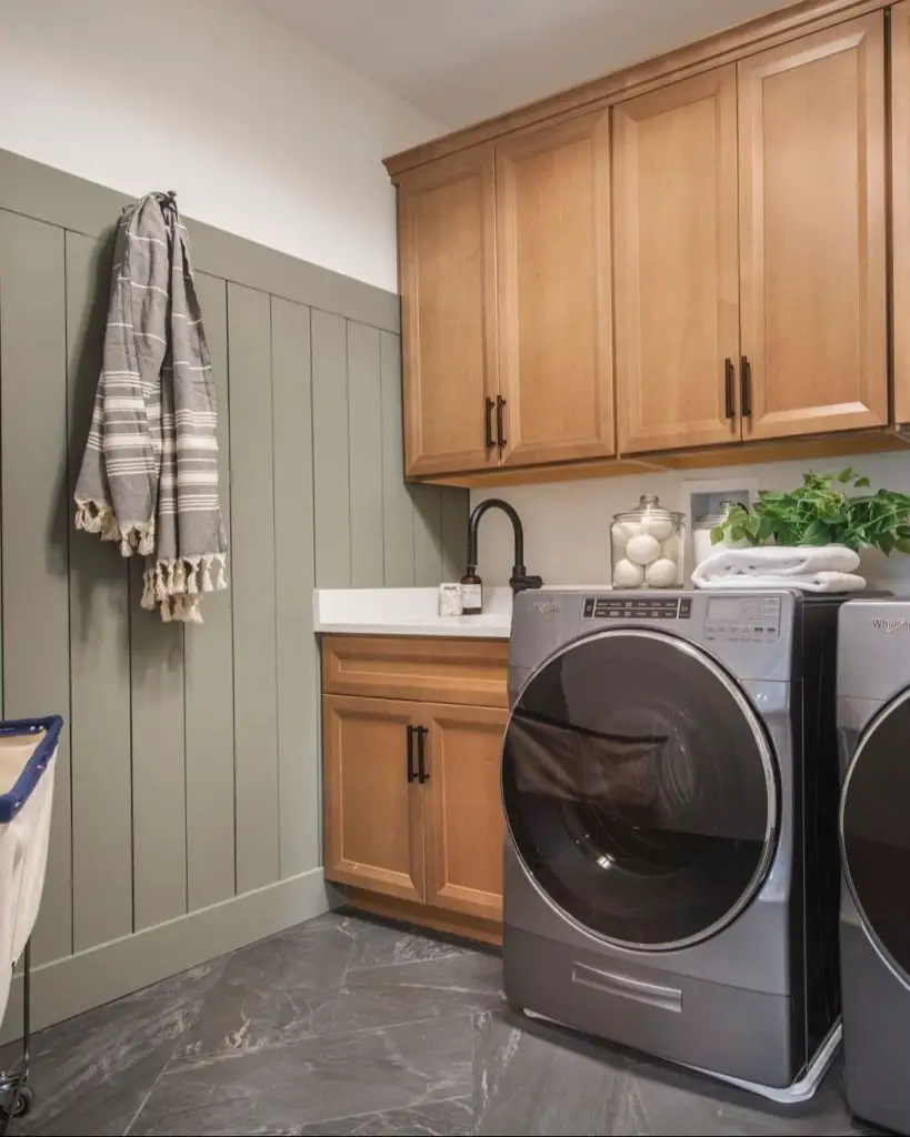 Cozy laundry room natural wood cabinets sage green walls marble floors