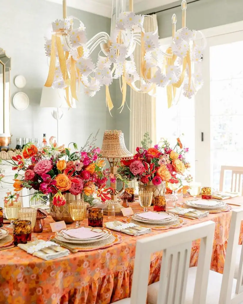 Daisy chandelier over coral floral tablescape with amber glassware and peach tablecloth