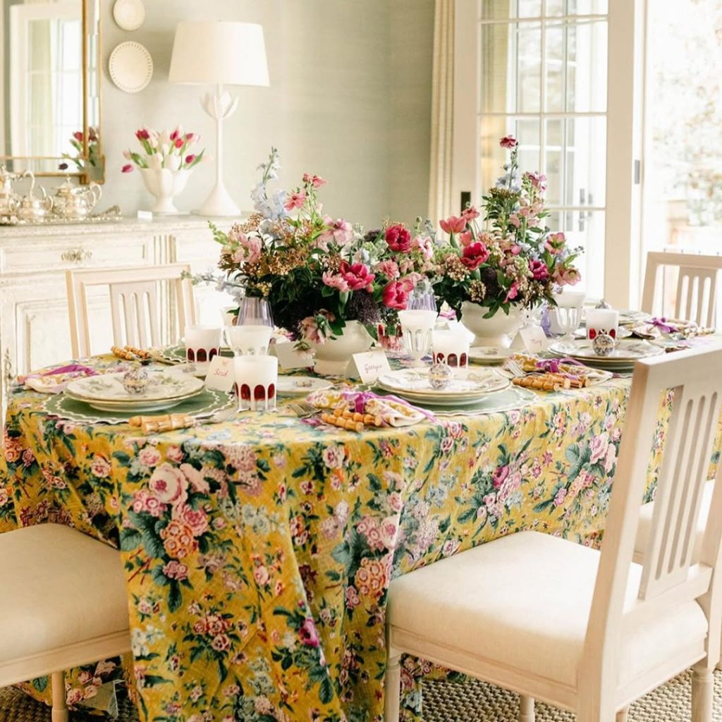 Yellow floral tablecloth with pink flower centerpieces and vintage tea settings