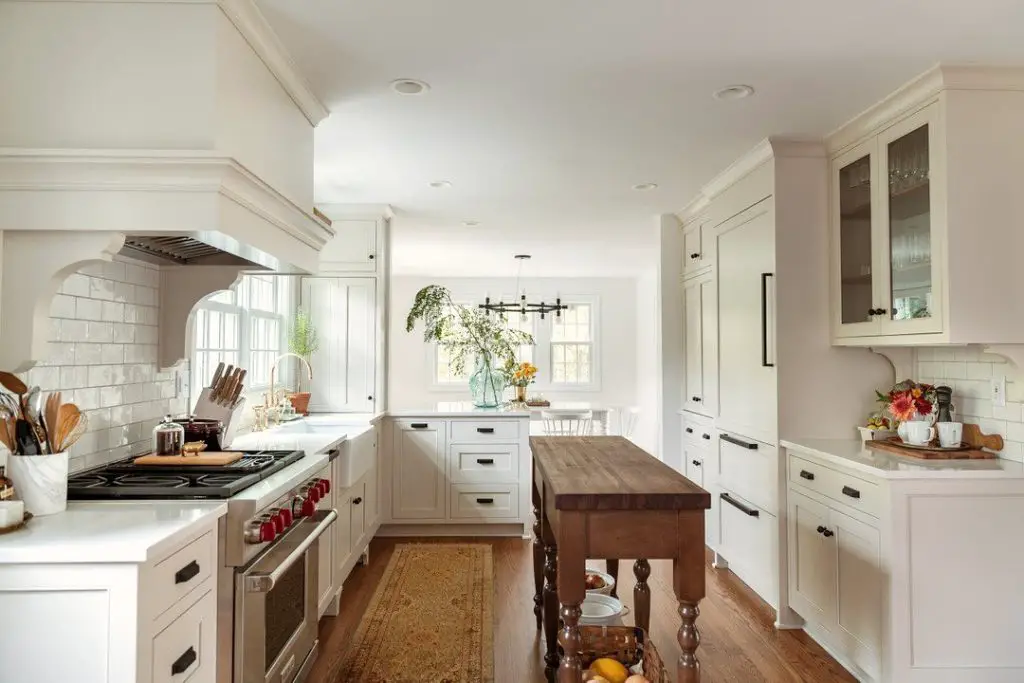 Bright white kitchen with wooden island and arched backsplash