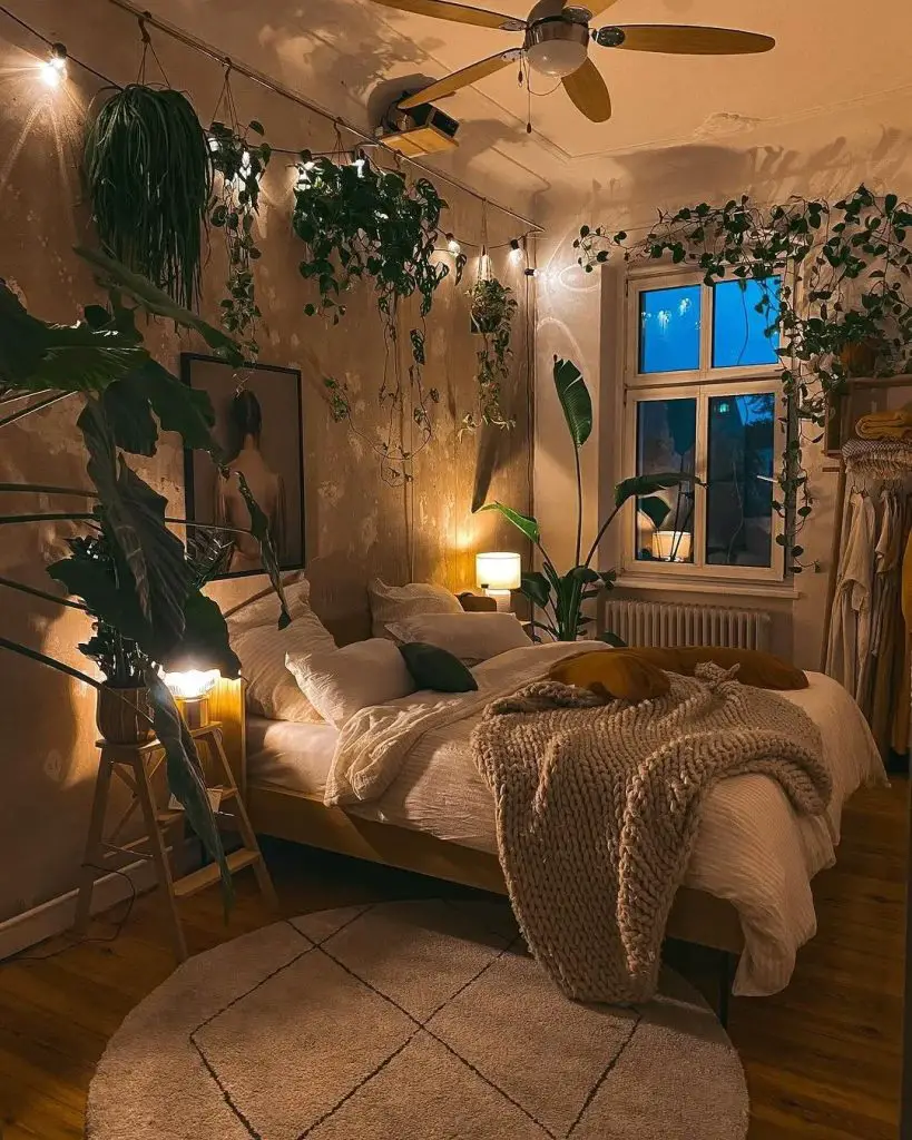 Cozy nighttime bedroom with hanging plants string lights and white bedding under moody lighting