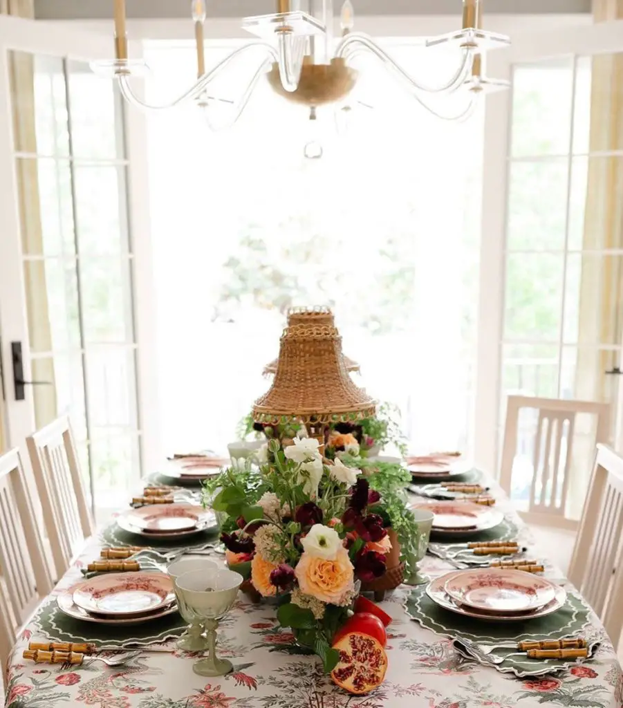 Elegant dining table with pagoda lantern centerpiece vintage plates and fresh floral arrangements under crystal chandelier