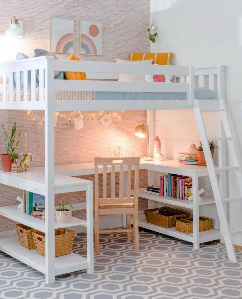 White loft bed with pink wallpaper desk area and woven storage baskets.