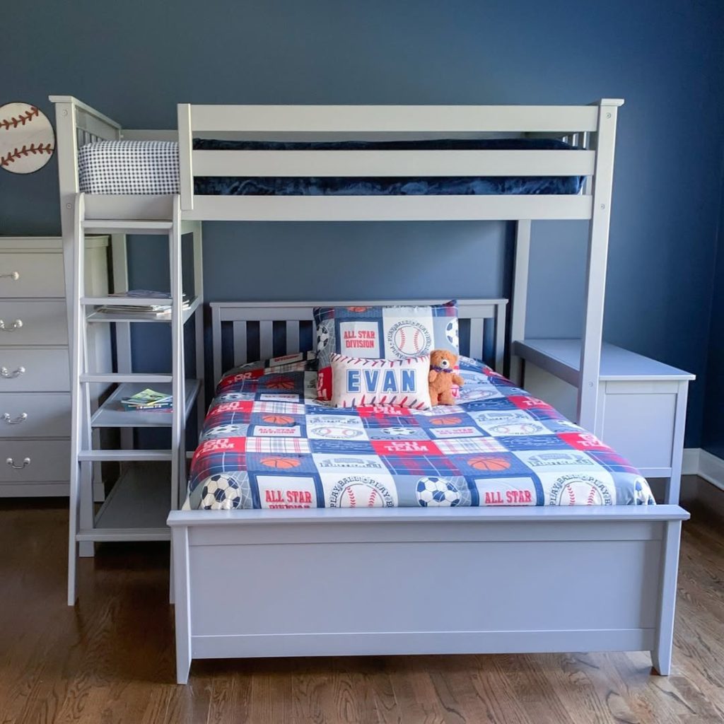 White bunk bed with sports themed bedding and built in ladder storage.