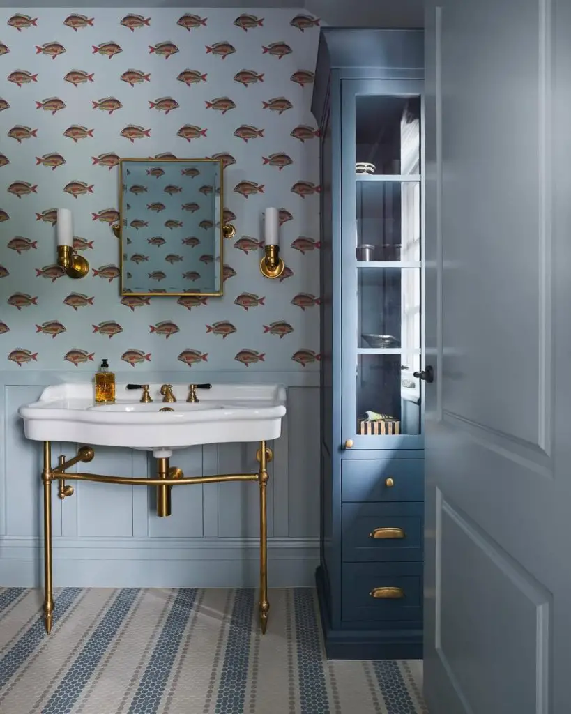 Blue bathroom with fish wallpaper and brass fixtures