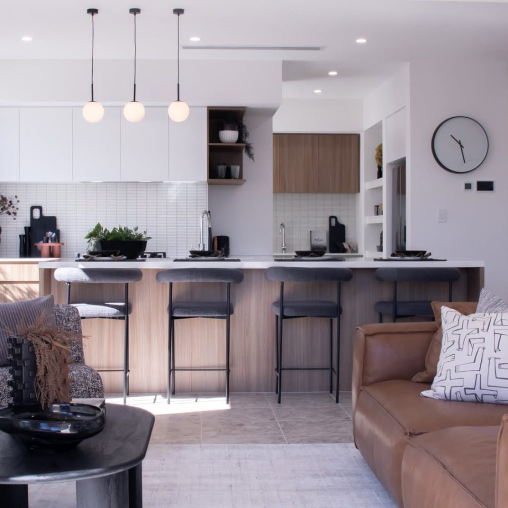 Modern kitchen with globe pendants and gray bar stools against white backsplash
