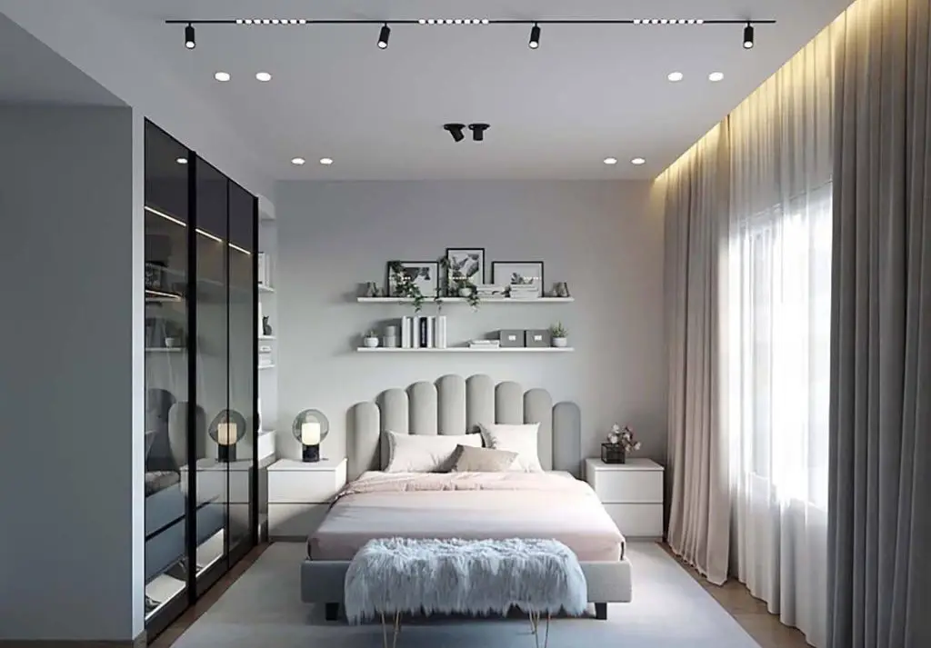 Modern grey bedroom with scalloped headboard and floating shelves displaying artwork