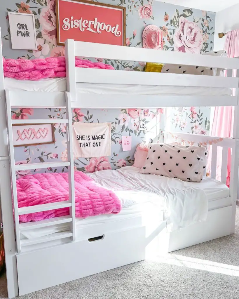 White bunk bed with pink decor and floral wallpaper sisterhood theme