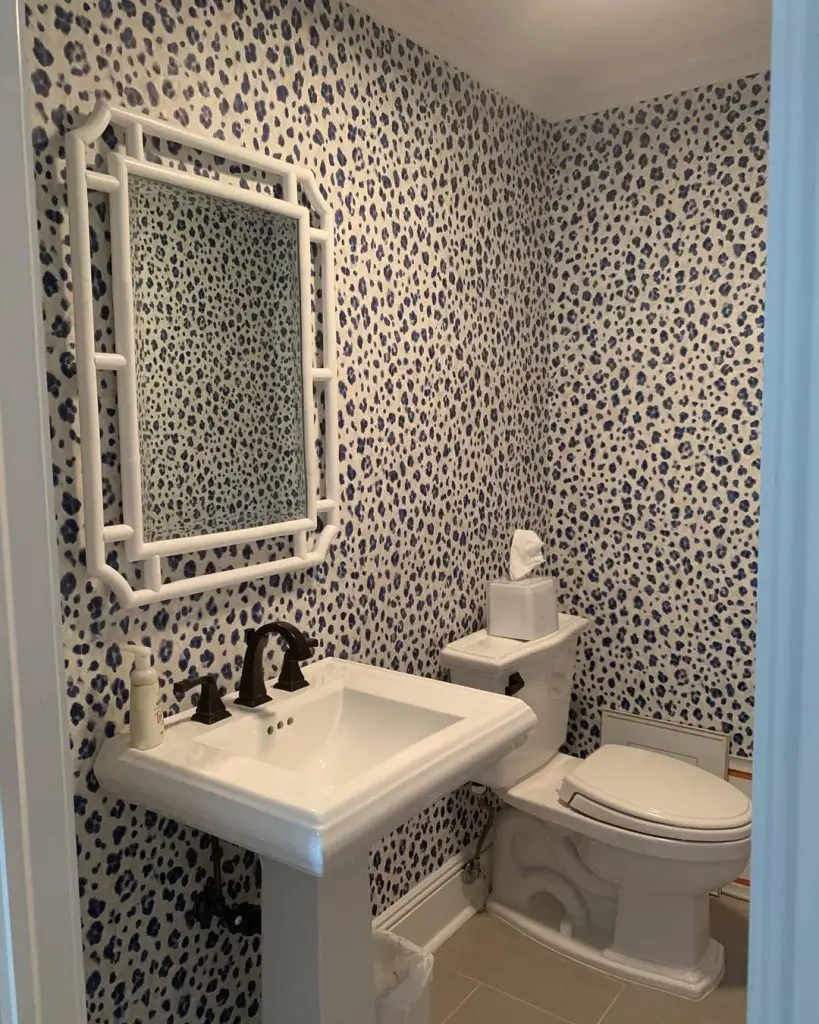 Powder room with navy leopard print wallpaper and white bamboo mirror