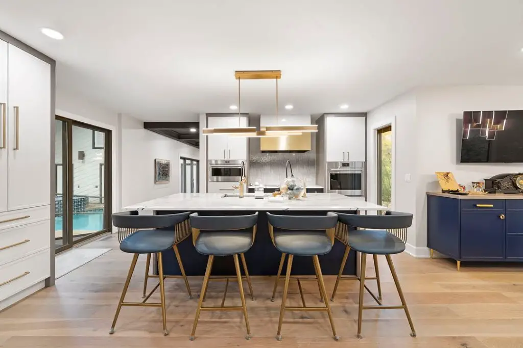 Modern kitchen featuring navy island and gold accent lighting