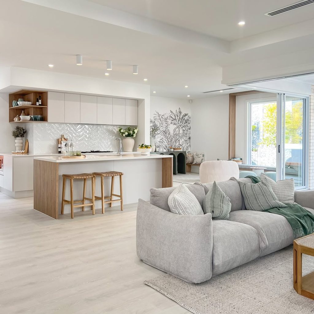 Bright white kitchen with wood accents and gray sectional sofa