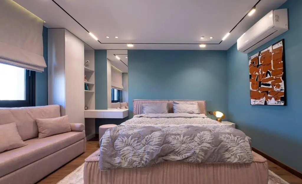 Modern bedroom with teal walls built in vanity and grey bedding