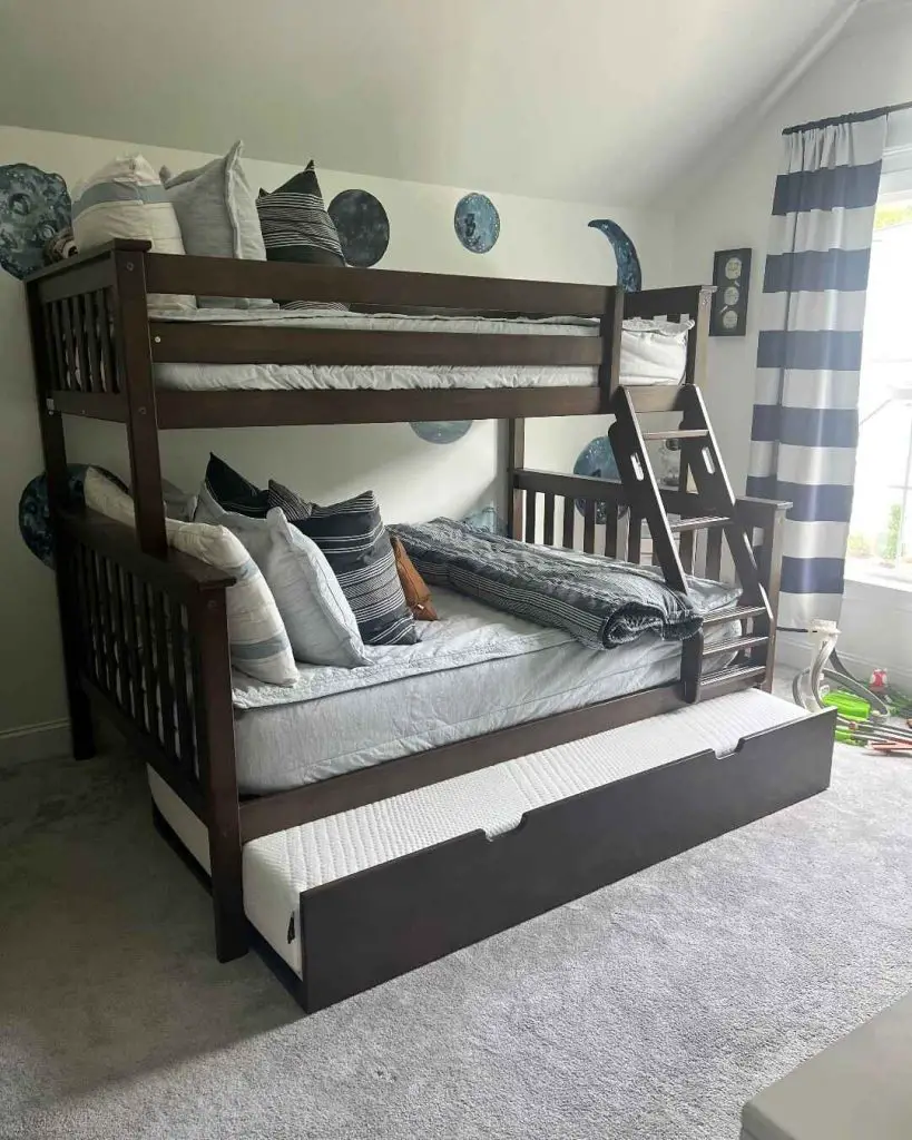 Dark wood bunk bed with moon phases wall art and trundle storage