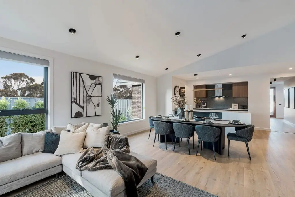 Modern living space with gray sectional and teal dining chairs