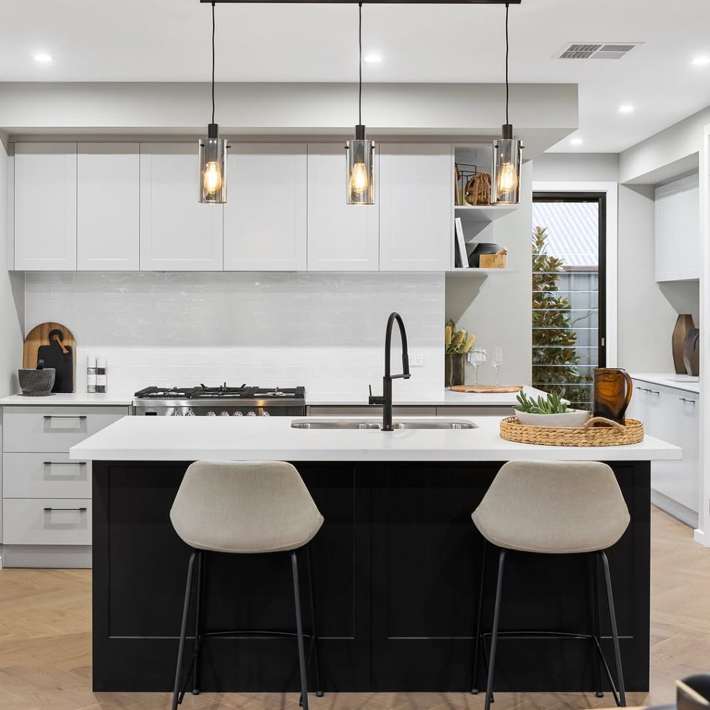 Contemporary black and white kitchen with pendant lights and modern stools