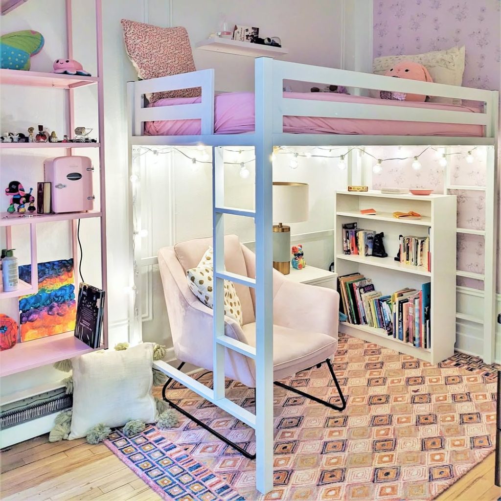 White loft bed with pink bedding floating above reading nook with string lights