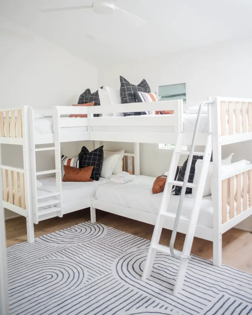 White bunk beds with abstract patterned bedding and geometric rug