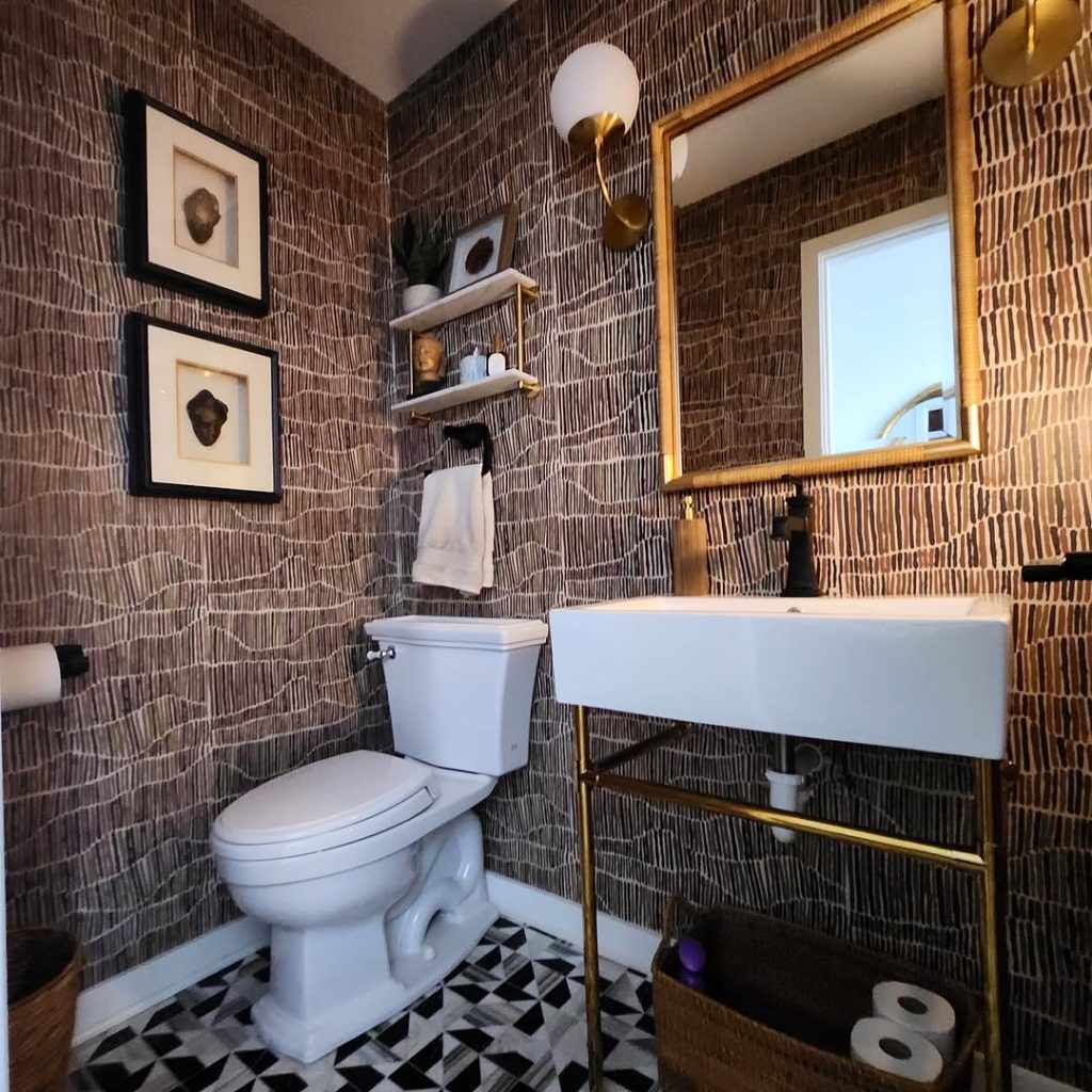 Modern powder room with brown patterned wallpaper and gold fixtures