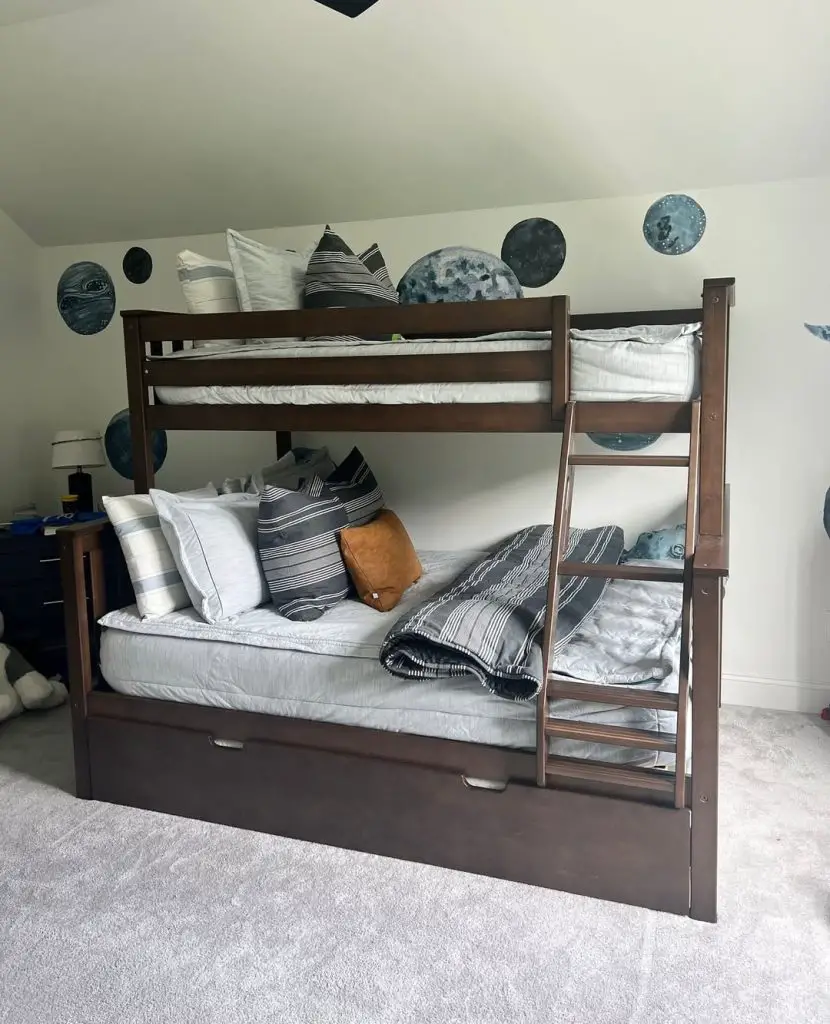 Dark wooden bunk bed with moon phase wall decor and striped bedding.