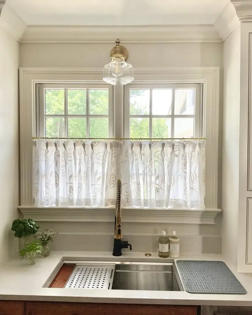 Bright kitchen with farmhouse sink and leaf-patterned curtain