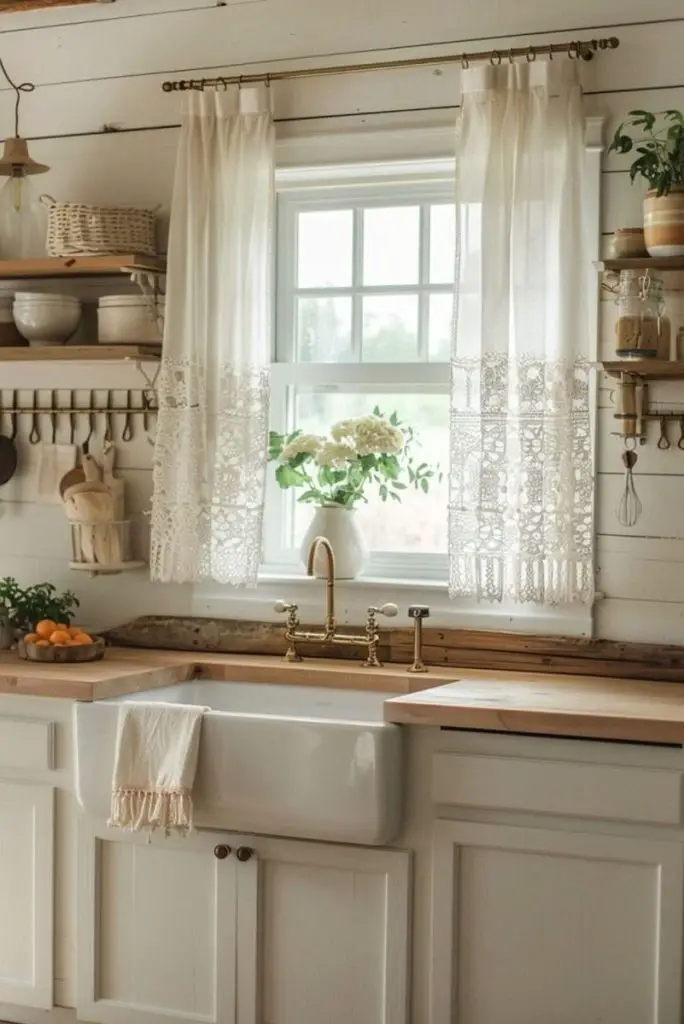 Charming farmhouse kitchen with sink, lace curtains, and fresh flowers.