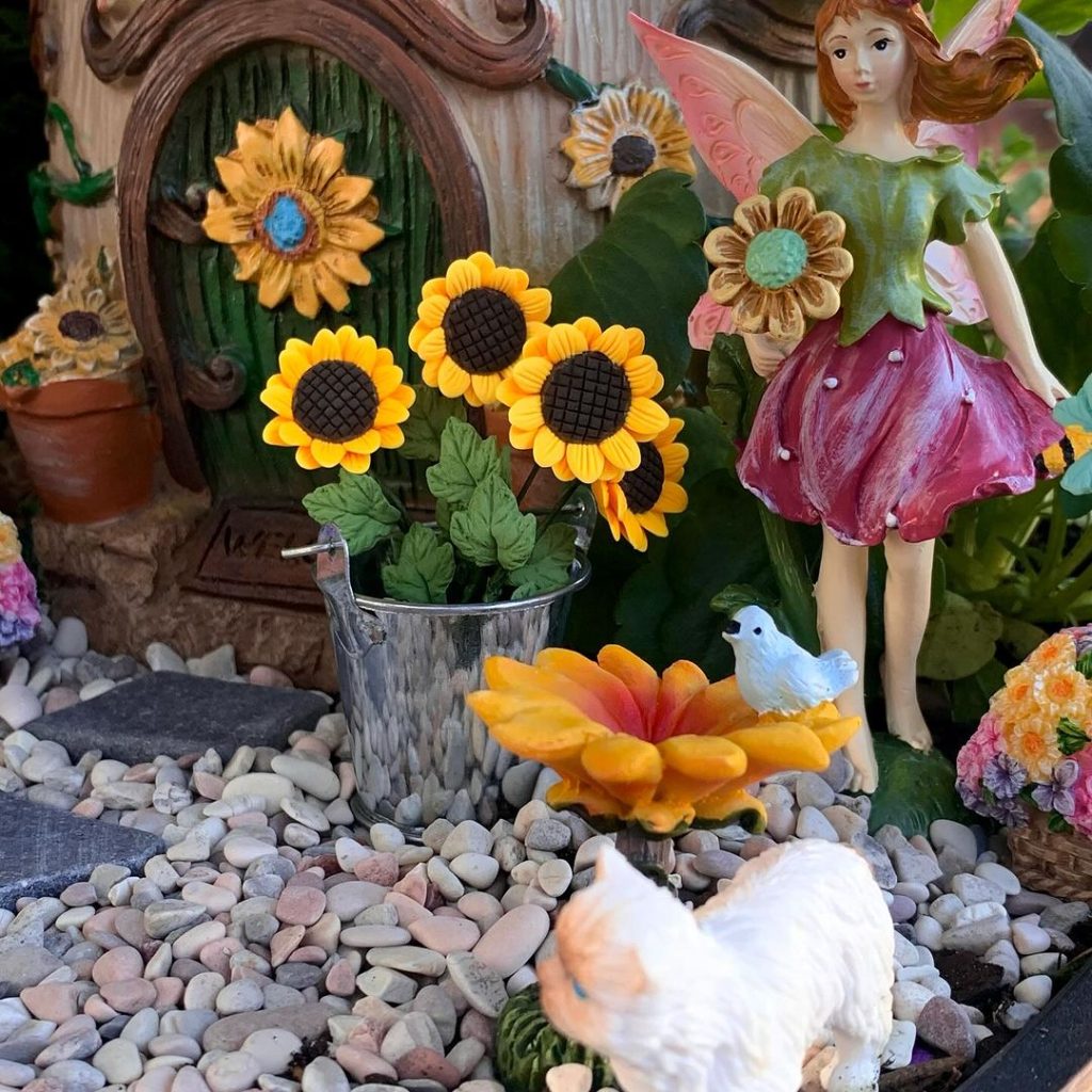 Fairy garden with sunflowers, fairy figure, and decorative elements