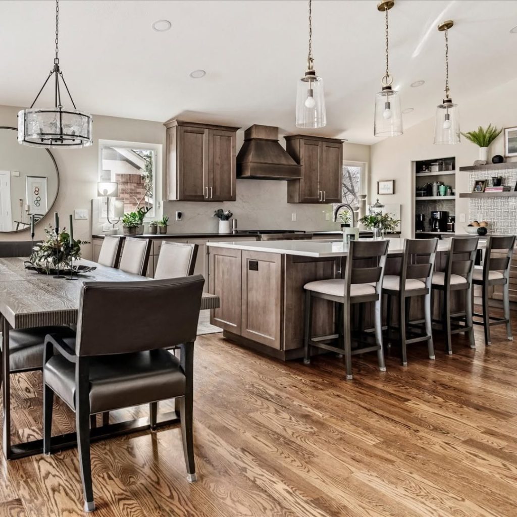 Open-concept kitchen with brown cabinets, white island countertop, and a rustic dining table