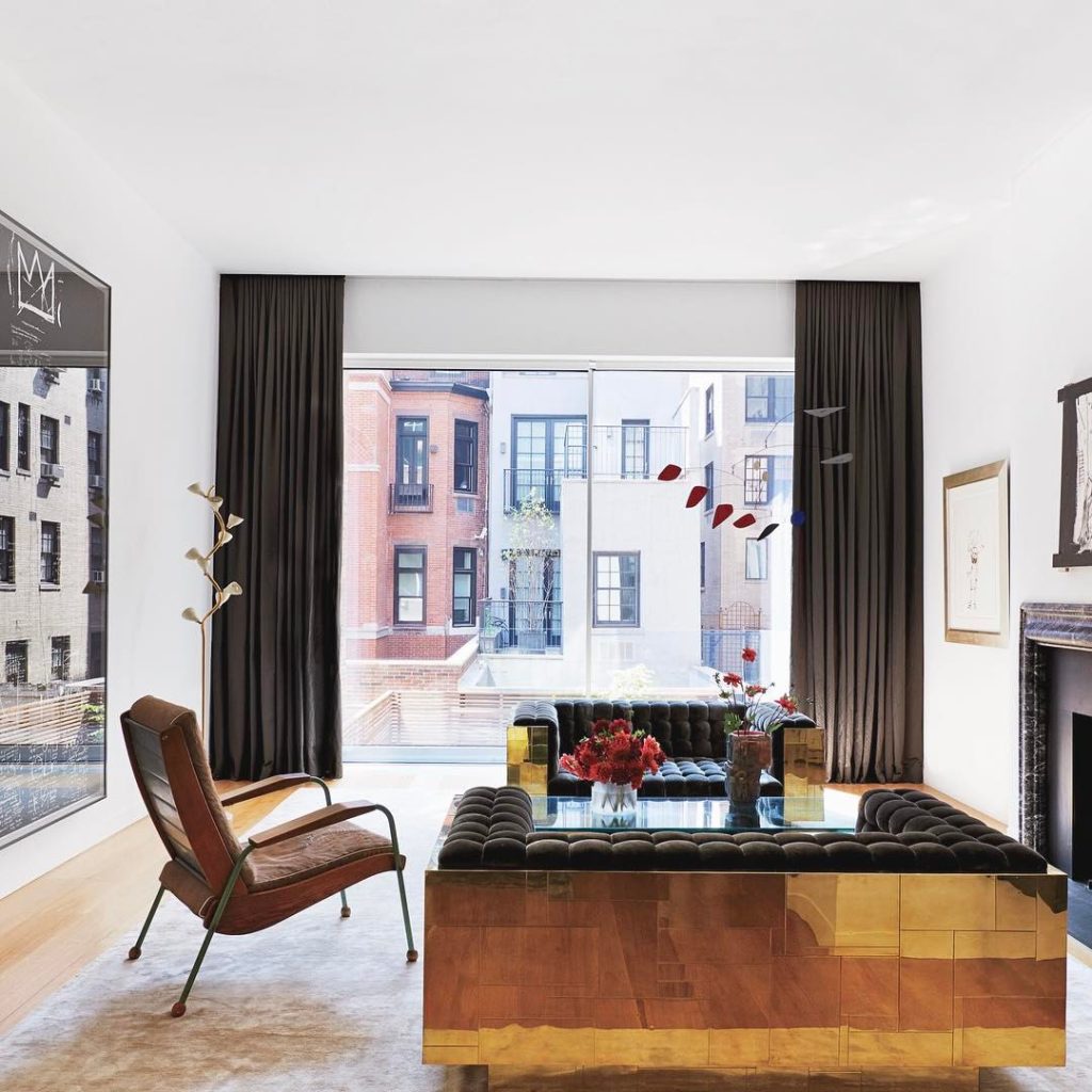 Modern living room with gold modular sofa, city view through large windows, and urban-inspired decor.