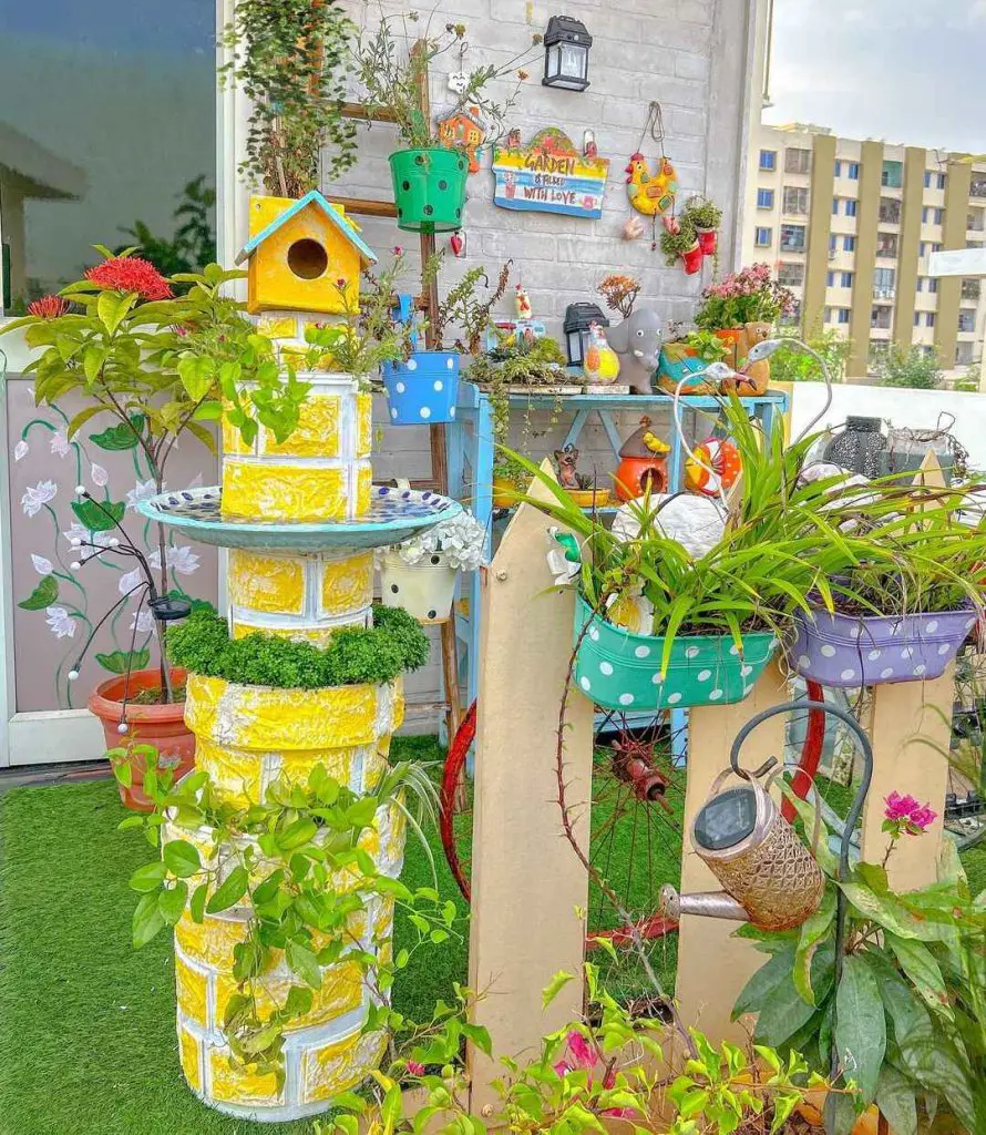 Rooftop garden with a yellow planter tower, colorful pots, and greenery.