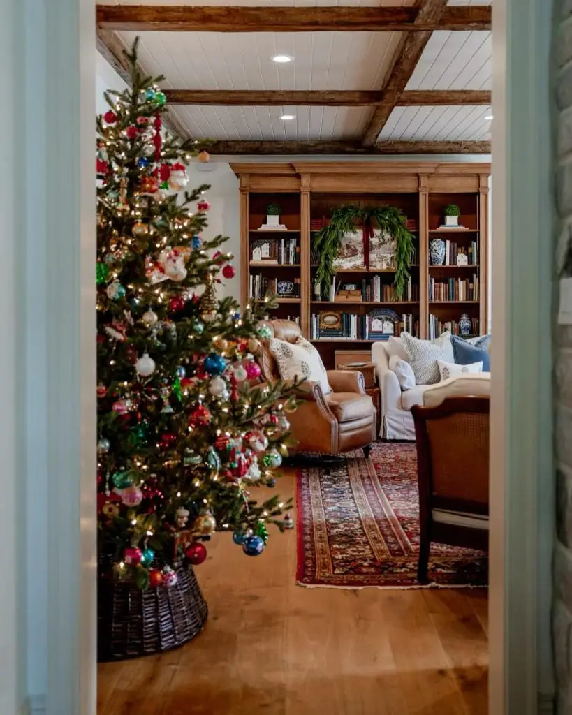 Cozy living room featuring a colorful Christmas tree and a bookshelf.