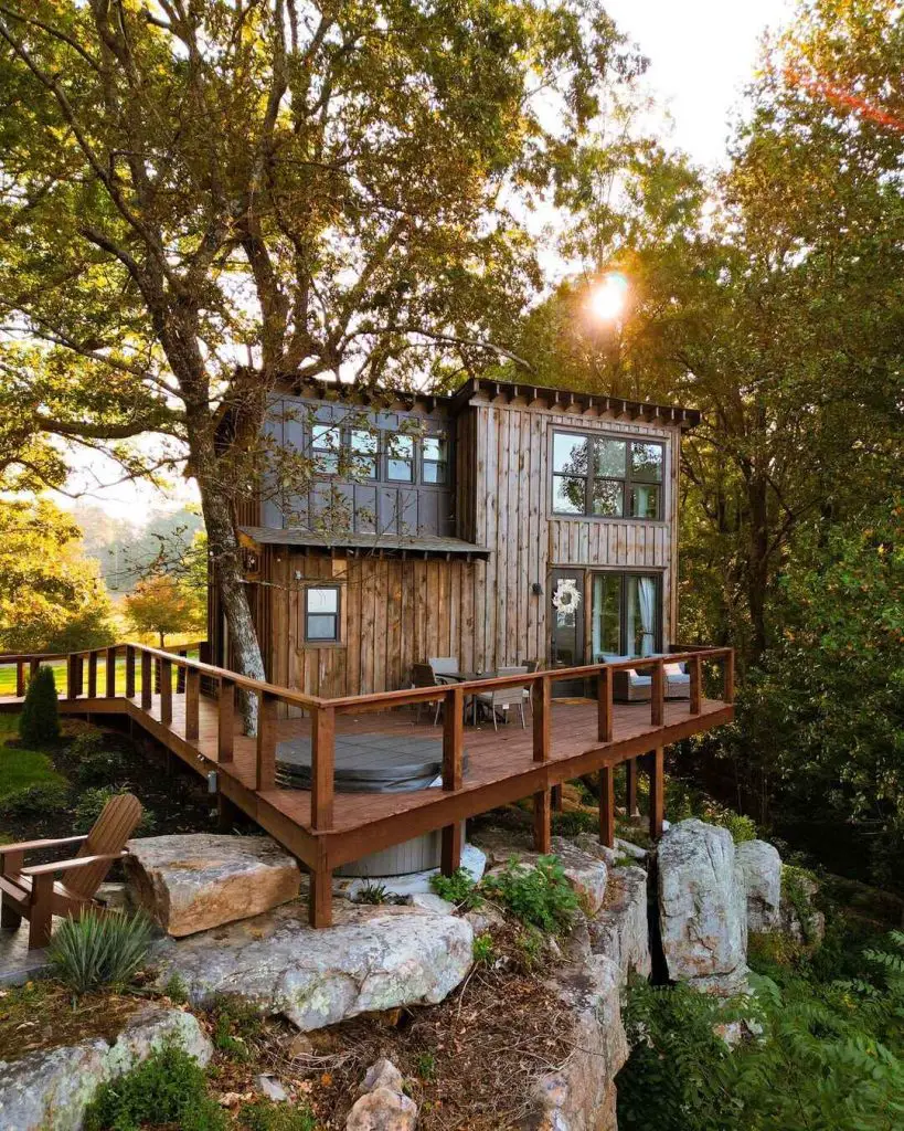 Charming cabin on a rocky outcrop with a deck and hot tub surrounded by trees