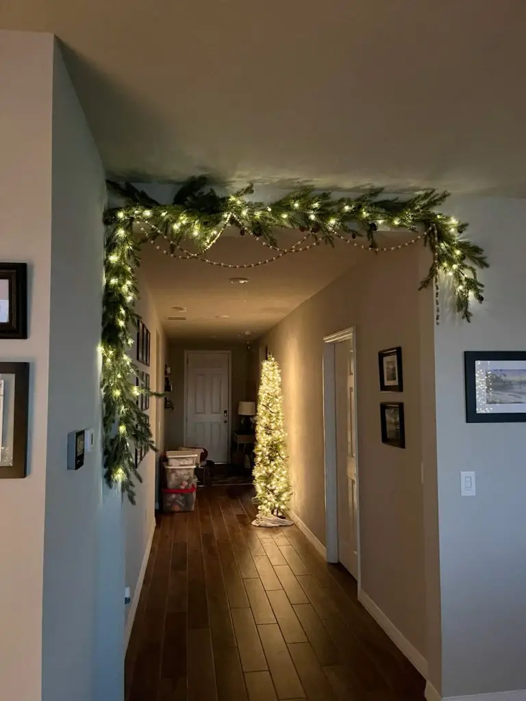 Festive hallway with lit garland and slim tree