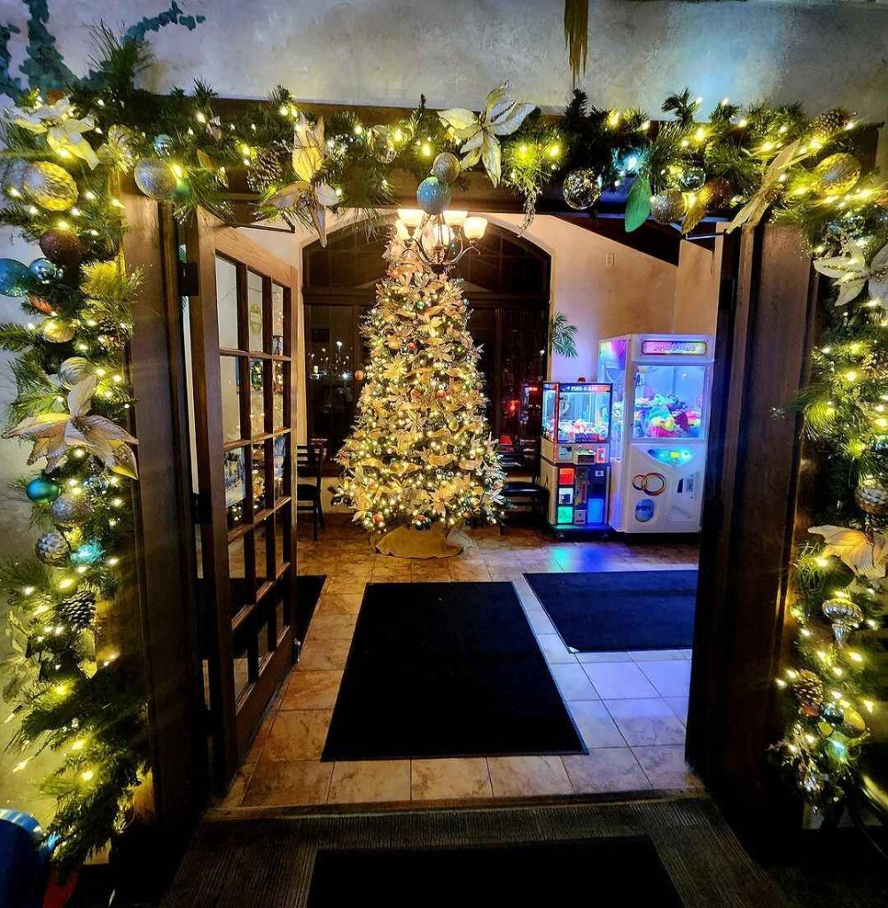 Festive entrance featuring a glowing Christmas tree and decorative garland