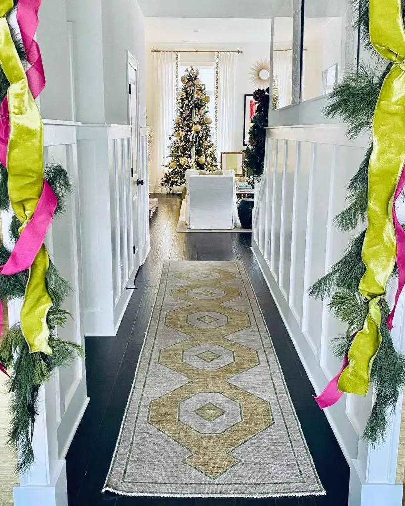 Festive hallway decorated with greenery and ribbons, leading to a Christmas tree