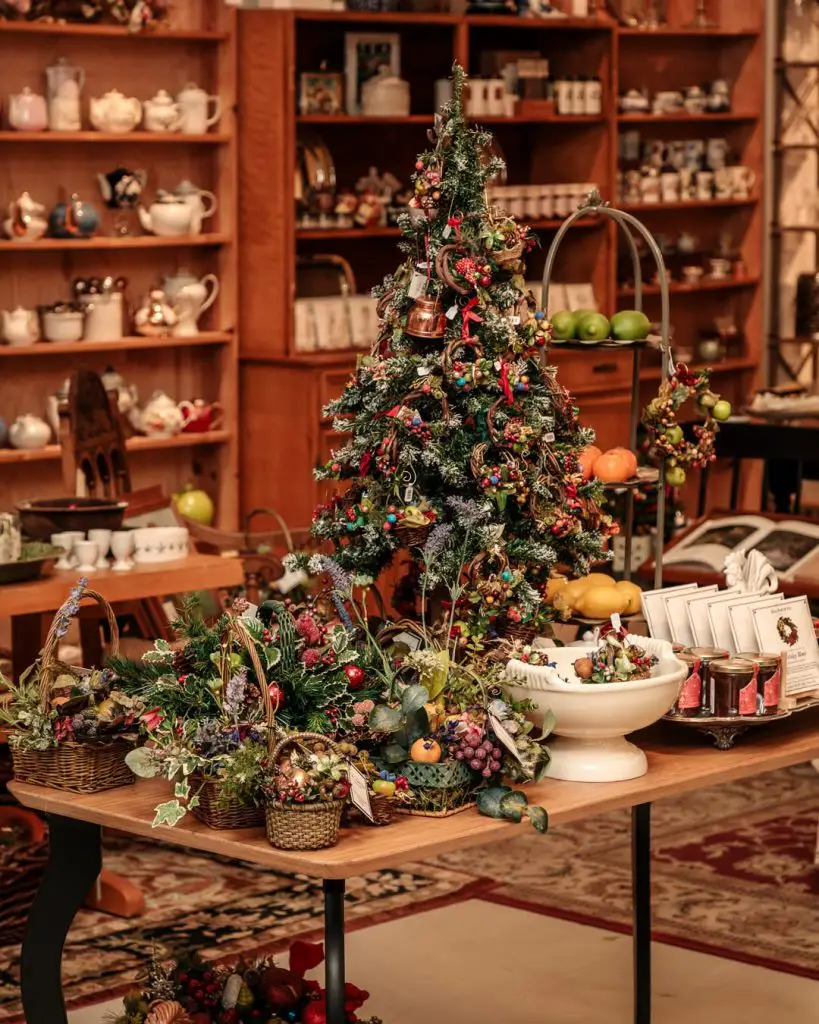 Decorated Christmas tree on a table surrounded by festive baskets and vintage items.