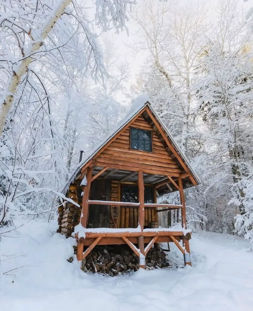 Snow-covered log cabin nestled in pristine white winter forest