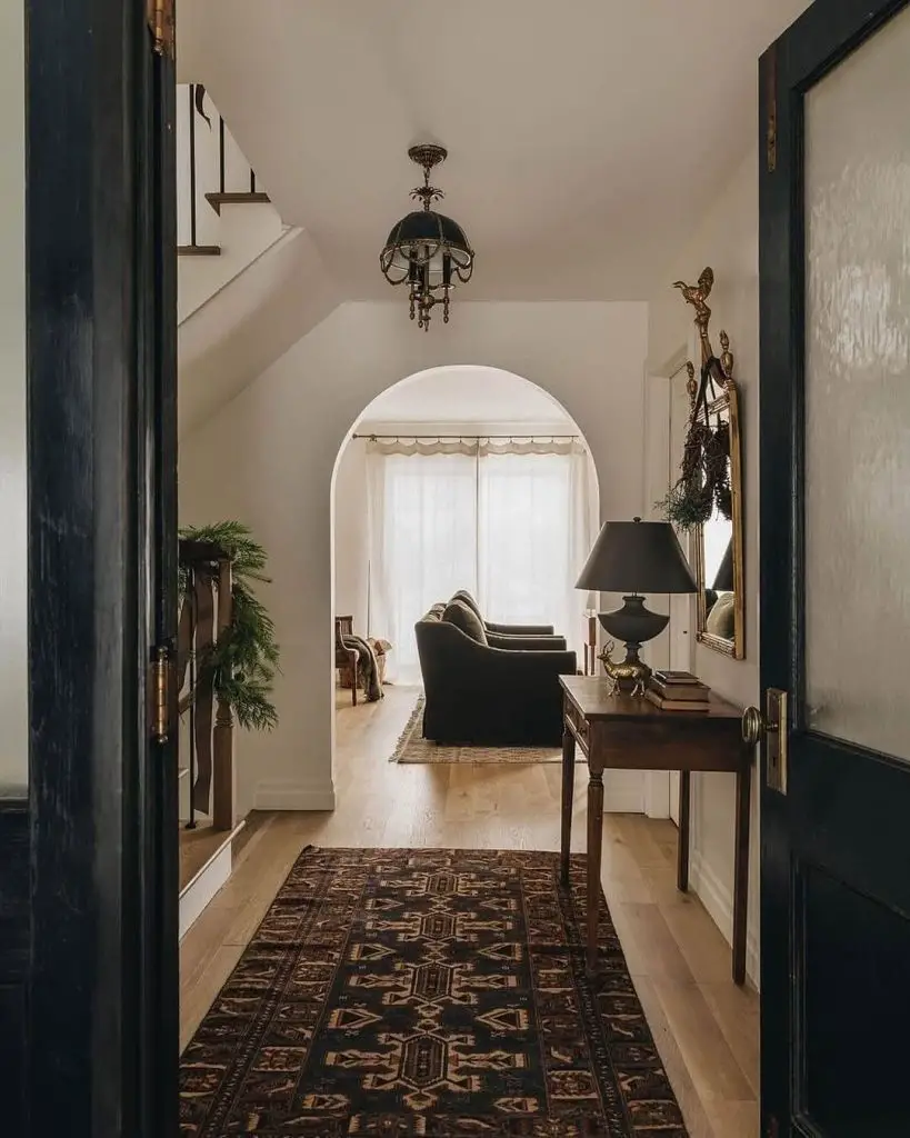 Inviting hallway with a patterned runner, chandelier, and view of a living room