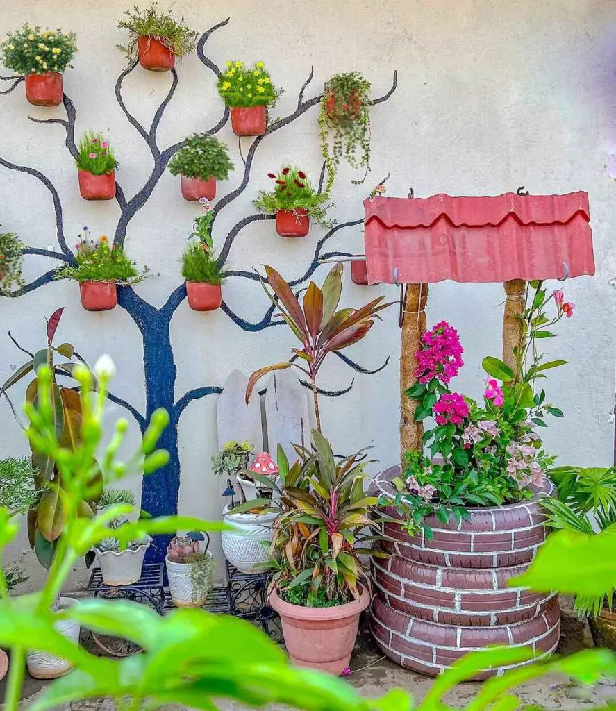 Garden wall with a painted tree and terracotta pots, featuring a decorative well
