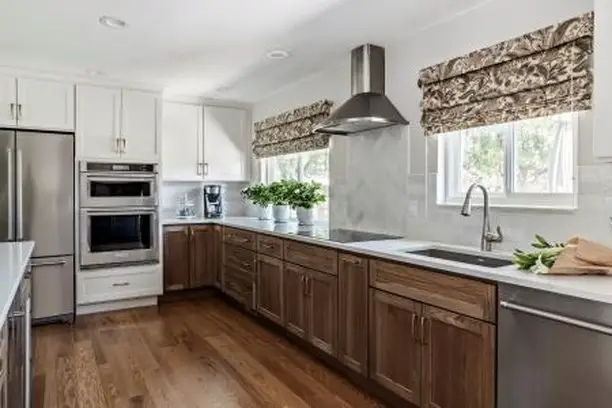 Modern kitchen with white cabinets, wooden accents, and stainless steel appliances.