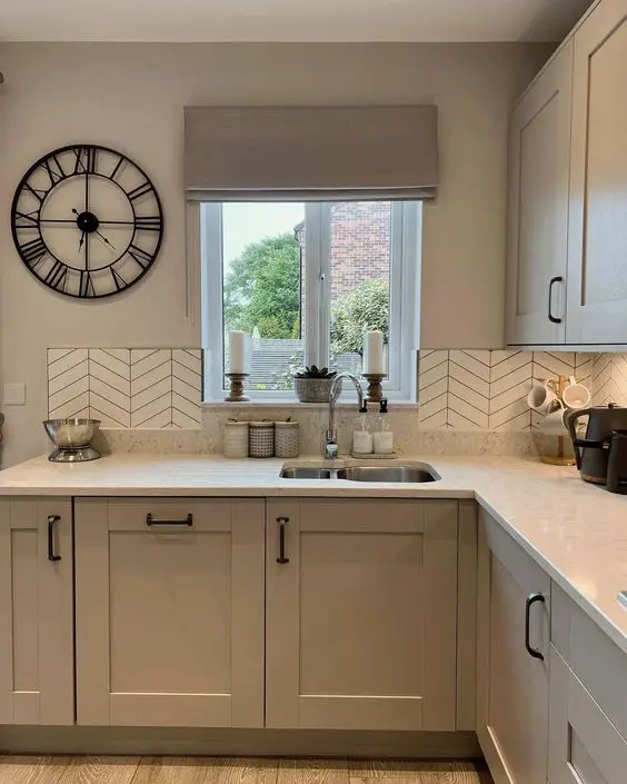 Modern kitchen with farmhouse sink, chevron backsplash, and wall clock