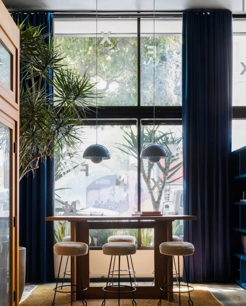 Chic dining nook with navy curtains, high-top table, and city view
