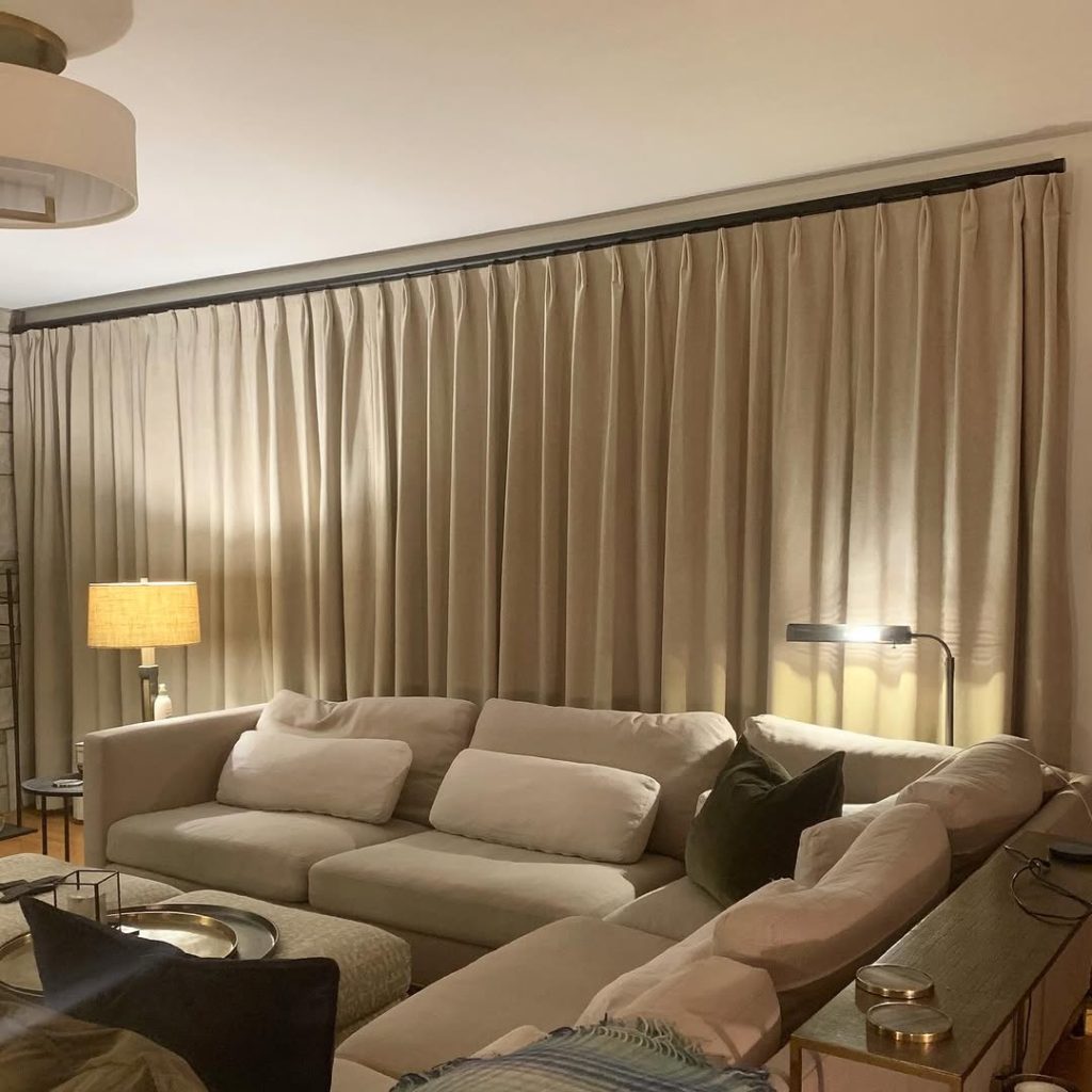 Cozy living room with beige curtains and large cream sectional sofa