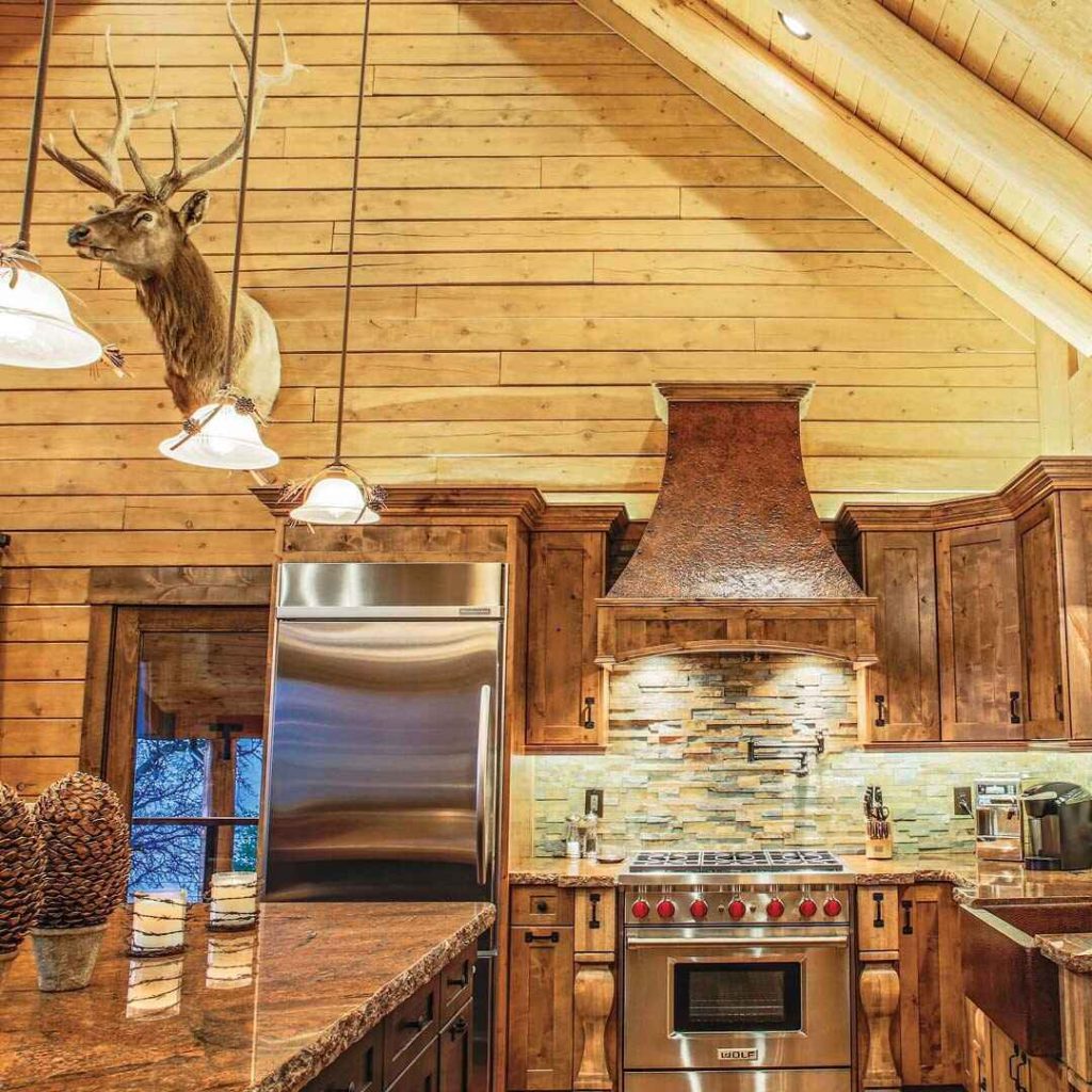Rustic mountain kitchen with wooden cabinets, stone backsplash, and copper range hood.